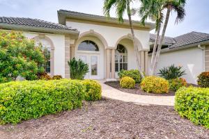 ein Haus mit Palmen und Büschen davor in der Unterkunft Private Pool, Dock and Gulf Access Cape Coral Home! in Cape Coral
