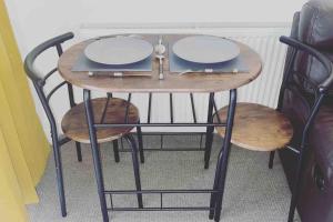 una mesa pequeña con dos taburetes y platos. en Cosy flat close to city centre., en Nether Edge
