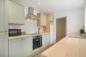 a kitchen with white cabinets and a black microwave at Lovely 2-Bedroom Home in Langley Park, Sleeps 4 in Durham