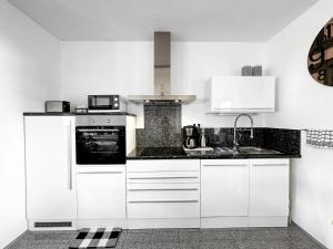 a kitchen with white cabinets and a sink at Ebony & Ivory Ferienwohnung in Steinhude