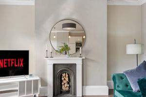 a living room with a fireplace and a mirror at Exquisite Georgian Apartment with Reserved Parking in Wakefield