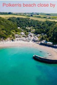 a boat sitting in the water next to a beach at Saint Chads Lodge Near EDEN Luxulyan in Luxulyan