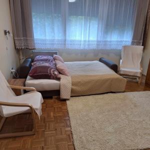 a bedroom with a bed and two chairs and a window at Gvadányi Rezidencia in Budapest