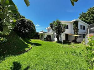 ein weißes Haus mit einem Garten mit grünem Gras in der Unterkunft Outstanding House in San Benito! in San Salvador