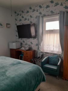sypialnia z łóżkiem, krzesłem i telewizorem w obiekcie The Chequers w mieście Great Yarmouth