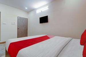 a white bedroom with a red and white bed and a tv at OYO Flagship Hotel Lavish Stay in Hyderabad