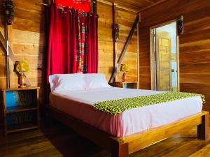 a bedroom with a bed and a red curtain at Monte Mar SãoTomé in M. Peixe
