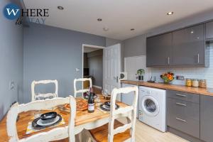 cocina con mesa de madera, lavadora y secadora en Stylish 3 Bedroom Apartment, Edinburgh, en Edimburgo