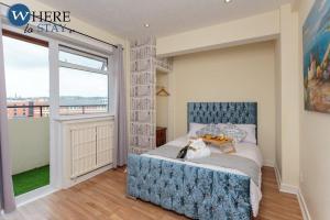 1 dormitorio con 1 cama con cabecero azul y ventana en Stylish 3 Bedroom Apartment, Edinburgh, en Edimburgo