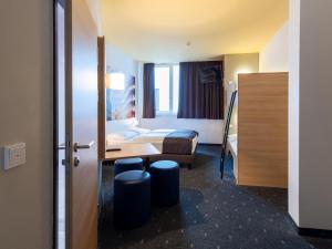 um quarto de hotel com uma cama, uma mesa e um banco em B&B Hotel Bayreuth em Bayreuth