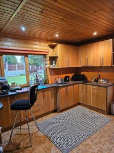 cocina con armarios de madera, silla y fregadero en Holiday house/Brīvdienu māja in Kegums, en Ķegums