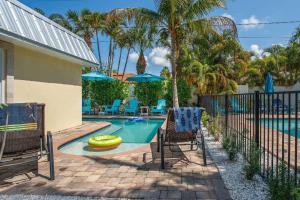 einen Pool mit zwei Stühlen und einem Zaun in der Unterkunft Lulu's Crescent Cottage #1 in Sarasota