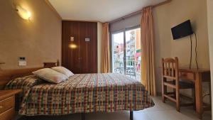 a small bedroom with a bed and a window at Hostal Los Maños in Blanes