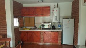cocina con armarios de madera y nevera blanca en Cabaña en El Trapiche Jotita Jota en Trapiche