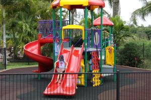 ein Kind auf einer Rutsche auf einem Spielplatz in der Unterkunft Brisbane Gateway Resort in Rochedale