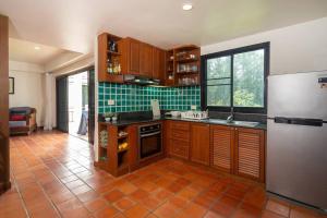 cocina con nevera y suelo de baldosa. en Beachside Apt Short Walk to Nai Harn Beach 2-3 BR, en Nai Harn Beach