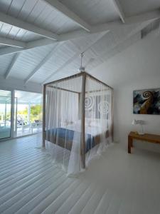 um quarto com uma cama de dossel num quarto branco em ITAKA LOMA BONITA em Las Terrenas