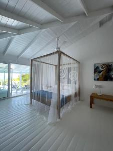 a bedroom with a canopy bed in a white room at ITAKA LOMA BONITA in Las Terrenas +44 photos
