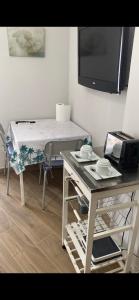 Zimmer mit einem Tisch und einem TV an der Wand in der Unterkunft Estudio sin habitación ,todo en una estancia Blanco Denia in Denia