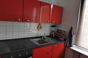 eine Küche mit roten Schränken und einem Waschbecken in der Unterkunft Private Apartment in Hannover