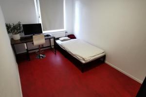 Kleines Zimmer mit einem Bett und einem Schreibtisch mit einem Computer. in der Unterkunft Private Apartment in Hannover