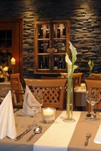 a table with a candle and a vase with a flower at Landhotel Lodge by Landhotel Krolik in Daun