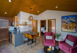 a kitchen and living room with pink chairs and a table at Bear Hill Lodge in Jasper
