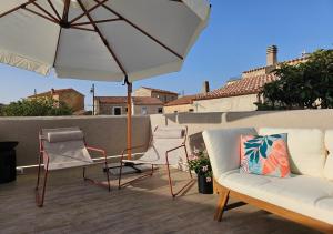 a patio with a couch and chairs and an umbrella at Rayuela Suites San Pantaleo in San Pantaleo