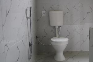un bagno con pareti in marmo e servizi igienici bianchi. di Kumirmari Ecotourism a Japur