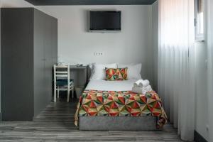 a bedroom with a bed with a tv on the wall at Residencial Kuarenta&Um in Barcelos