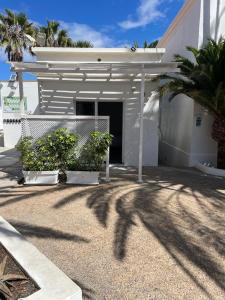 una casa blanca con una puerta y algunas plantas en Apartamentos Punta Elena Beach, en Corralejo