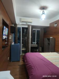 a bedroom with a purple bed and a view of the city at APARTEMEN GRAND DHIKA 2325 BEKASI TIMUR in Padurenan