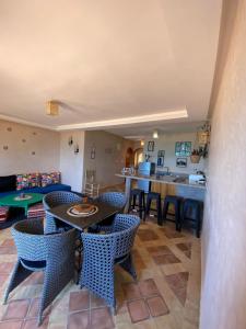 a living room with tables and chairs and a kitchen at Dar diafa samira in Mirleft