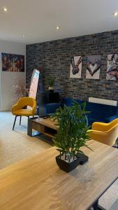 a living room with a blue couch and yellow chairs at Luxury beach front rooms- PMA in Kirkcaldy