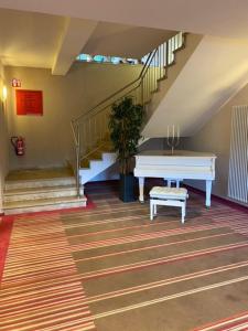 a staircase with a white piano in a room at Seehotel in Kell