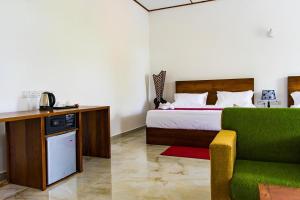 ein Hotelzimmer mit einem Bett und einem grünen Sofa in der Unterkunft Yala Hotel Elephant Eye in Tissamaharama