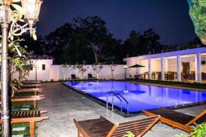 a swimming pool at night with benches around it at Yala Hotel Elephant Eye in Tissamaharama