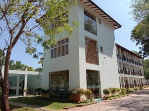 a white building with trees in front of it at Yala Hotel Elephant Eye in Tissamaharama