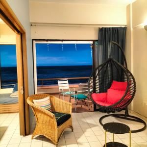 a room with a swinging chair and a balcony with the ocean at Seafront Corus Resort Port Dickson in Port Dickson