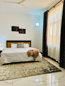 a bedroom with a bed and a large window at Lomes cozy home in Dar es Salaam