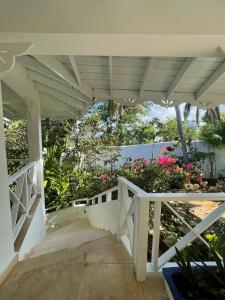 a white porch with a white railing and flowers at ITAKA LOMA BONITA in Las Terrenas