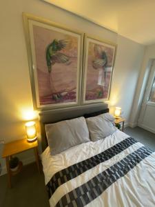 a bedroom with a bed with two pictures on the wall at Skylight Deluxe Apartment with free parking, close to Windsor, Legoland and Heathrow in Farnham Royal
