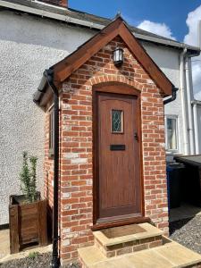 a brick house with a wooden door in front of a house at Shipmeadow Cosy Cottage in Beccles