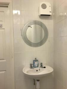 a white bathroom with a sink and a mirror at Shipmeadow Cosy Cottage in Beccles