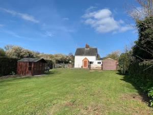 a large field with a barn and a house at Shipmeadow Cosy Cottage in Beccles