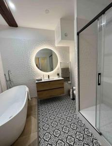 een badkamer met een bad, een wastafel en een spiegel bij Le Lamartine - vue Saône - Baignoire îlot in Mâcon
