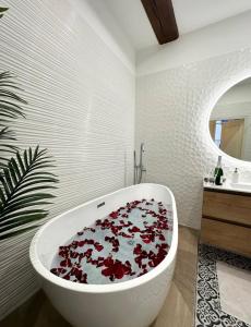 a bathroom with a white tub filled with red flowers at Le Lamartine - vue Saône - Baignoire îlot in Mâcon