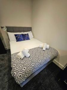 1 dormitorio con 1 cama con sábanas blancas y almohadas azules en Stunning City Center Prime Location Flat - TV in every bedroom en Neath