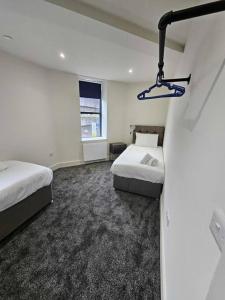 Habitación de hotel con 2 camas y ventana en Stunning City Center Prime Location Flat - TV in every bedroom, en Neath