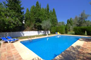 a swimming pool with two blue chairs and trees at Holiday Home La Cartuja in Jávea